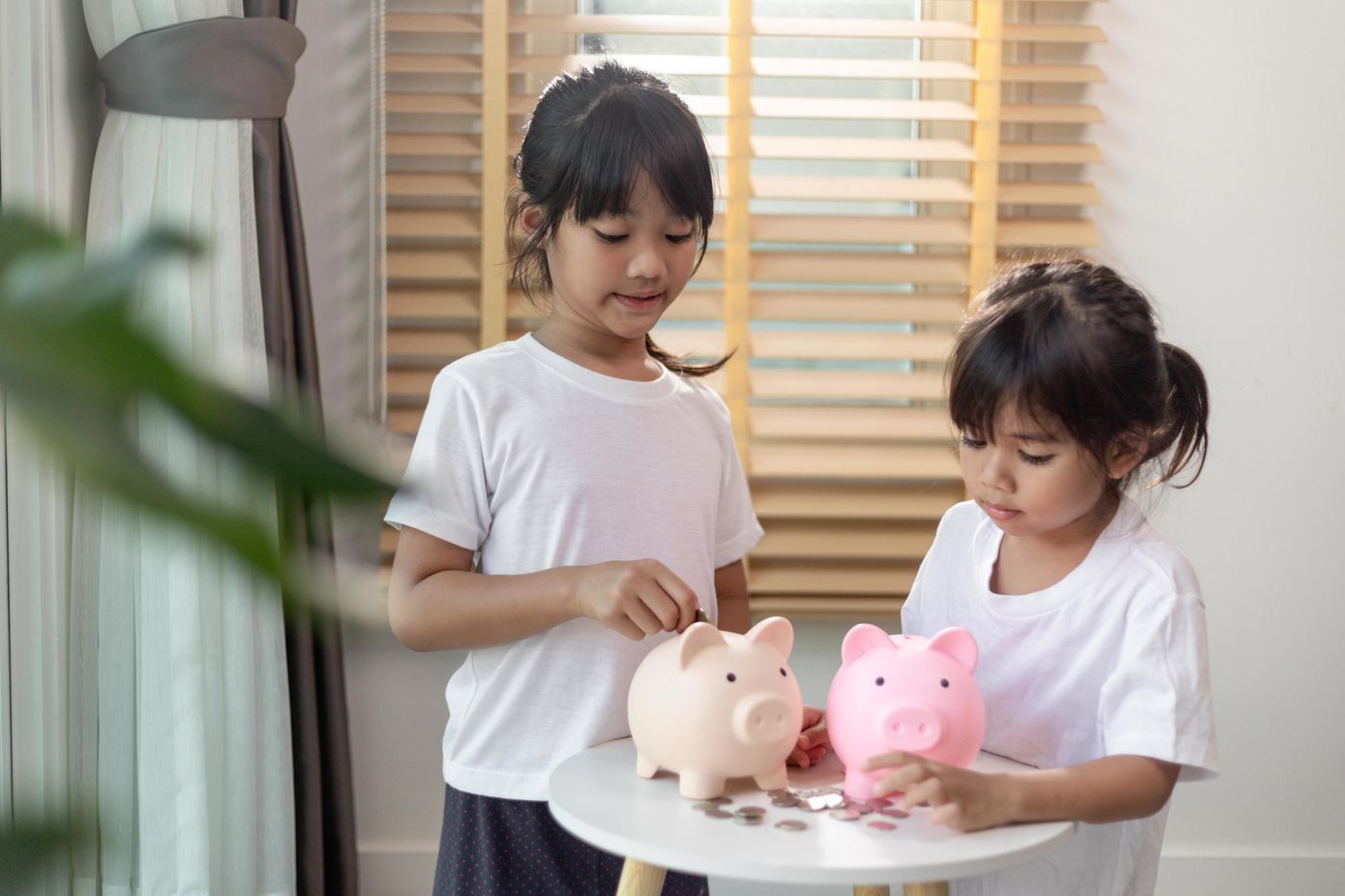 Little Asian girl saving money in a piggy bank, learning about saving, Kid  save money for future education. Money, finances, insurance, and