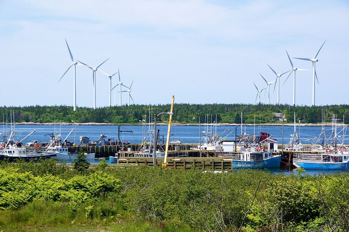 A government wharf in East Pubnico against the backdrop of the Pubnico Point Windfarm.