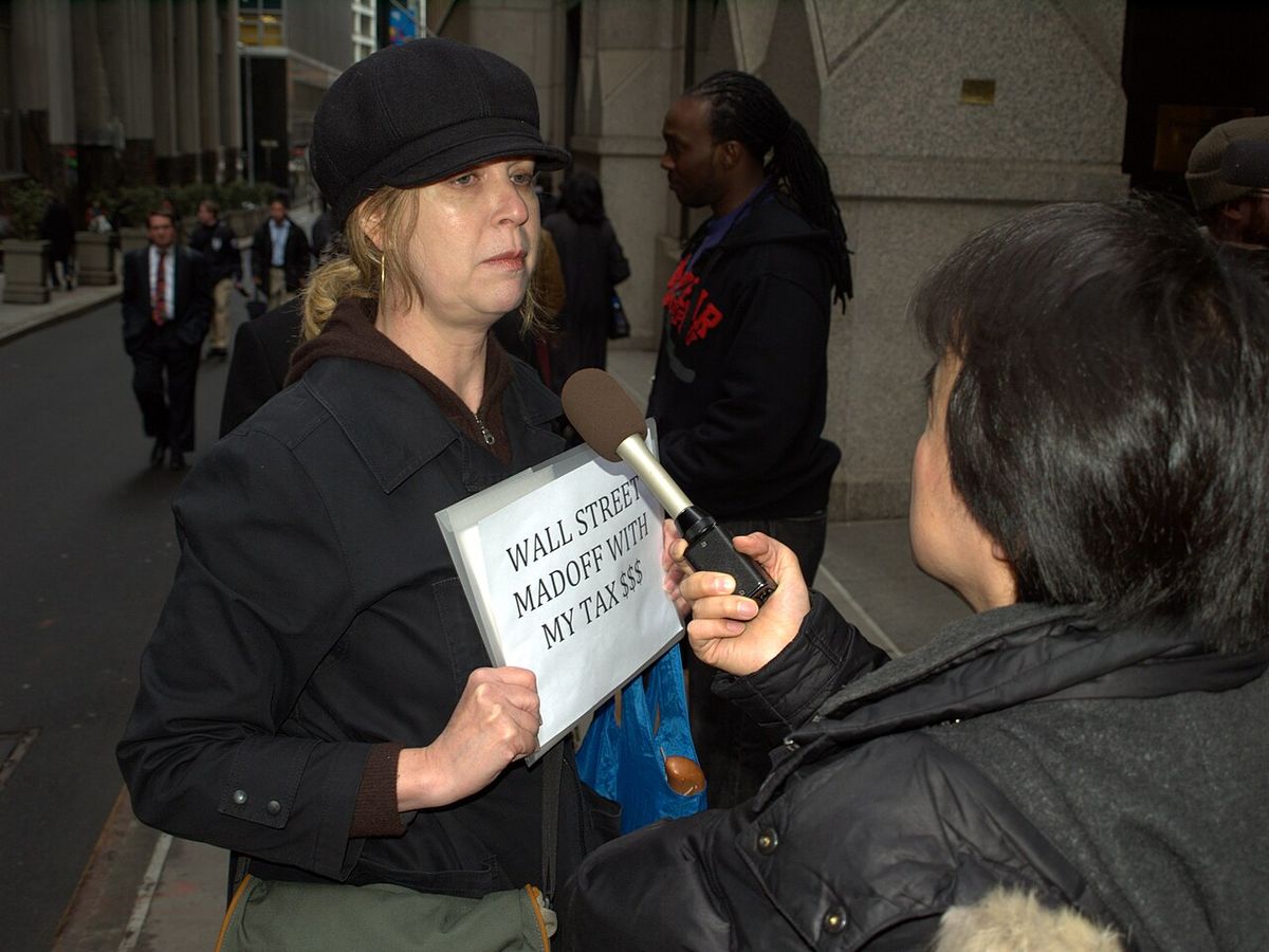 A protester outside AIG's headquarters at the American International Buildling in New York City is interviewed by a news crew. Photographer'