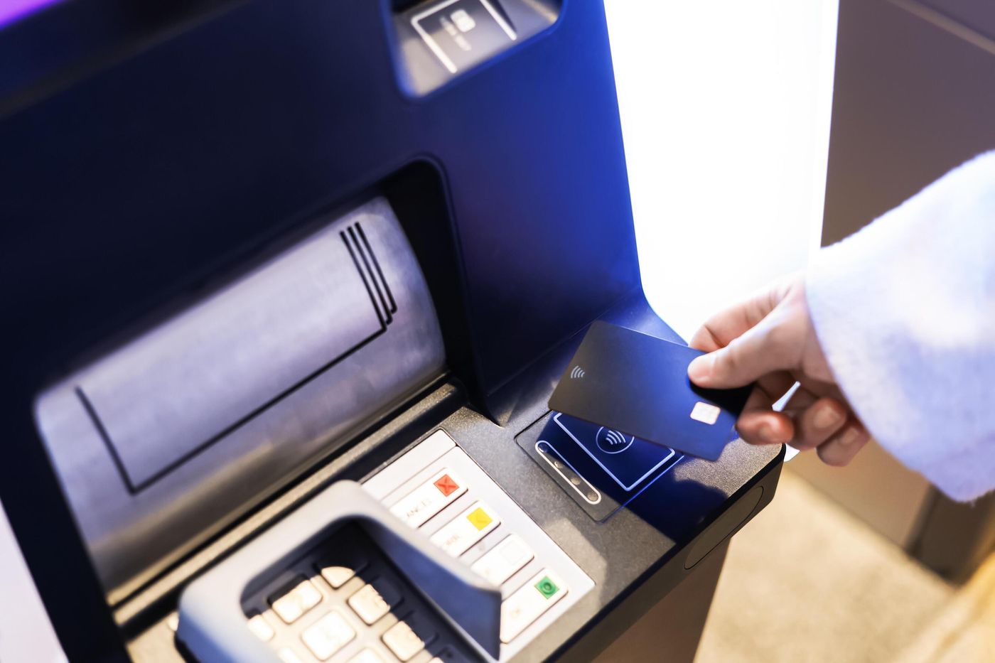 A person's hand inserting a black bank card into an ATM machine for a  contactless transaction, cash withdrawal, or deposit. 75530386 Stock 